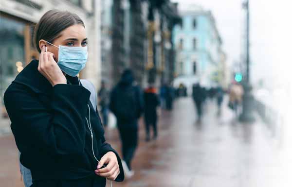 Prevention of coronavirus outbreak in 2020. Portrait of young european woman wearing a mask in the city street. Prevent pollution and disease concept.