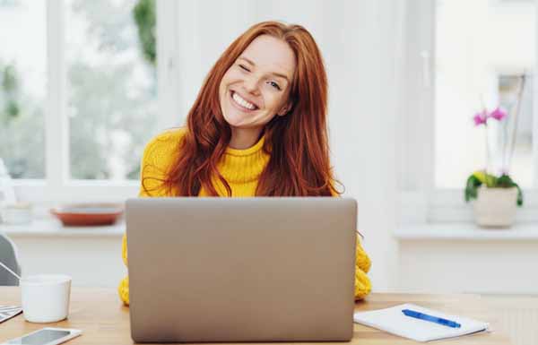 Young happy red-haired woman using laptop